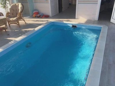 Прямоугольный бассейн с синей водой и зона отдыха на светлой плитке